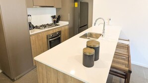 A modern kitchen with a central island, stainless steel appliances, and a built-in oven. - Beautiful Apartment in the Heart of Zapopan 306A (Zapopan)