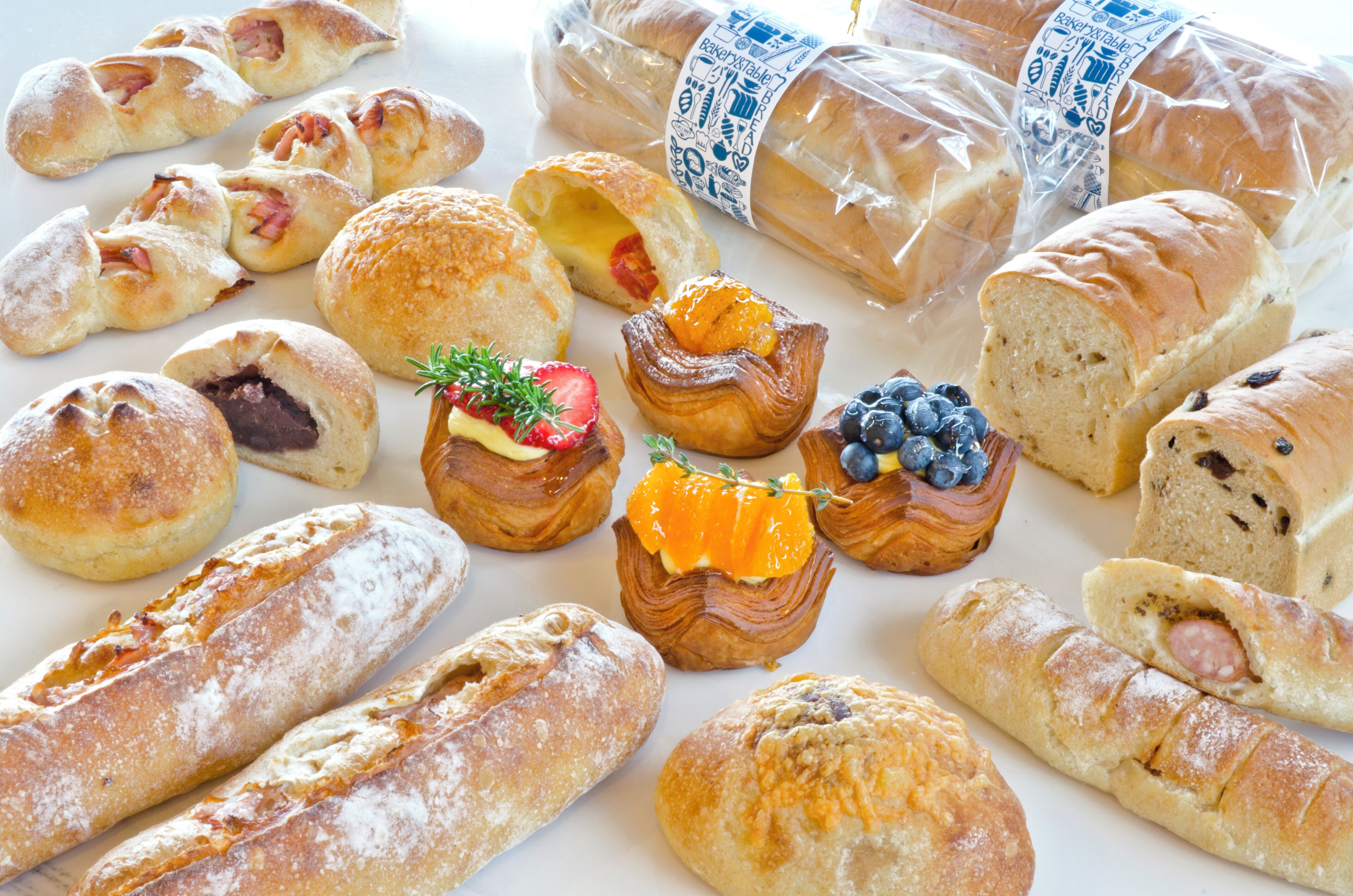 A variety of baked goods including pastries and bread, some with visible fillings like fruit and nuts.