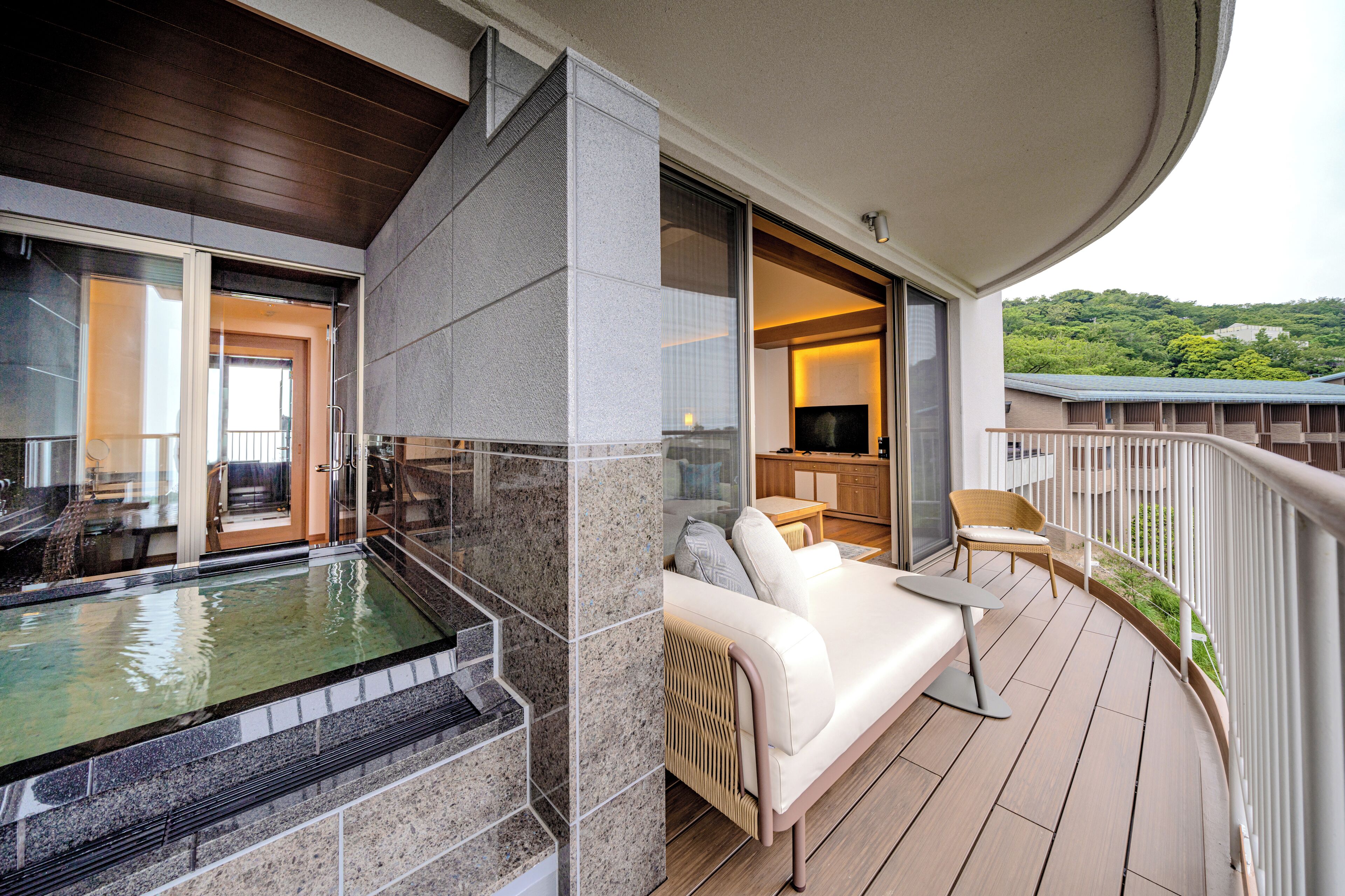 Ein Balkon mit Whirlpool, einer Couch und einem Fernseher.