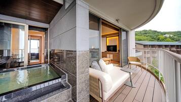 Ein Balkon mit Whirlpool, einer Couch und einem Fernseher.