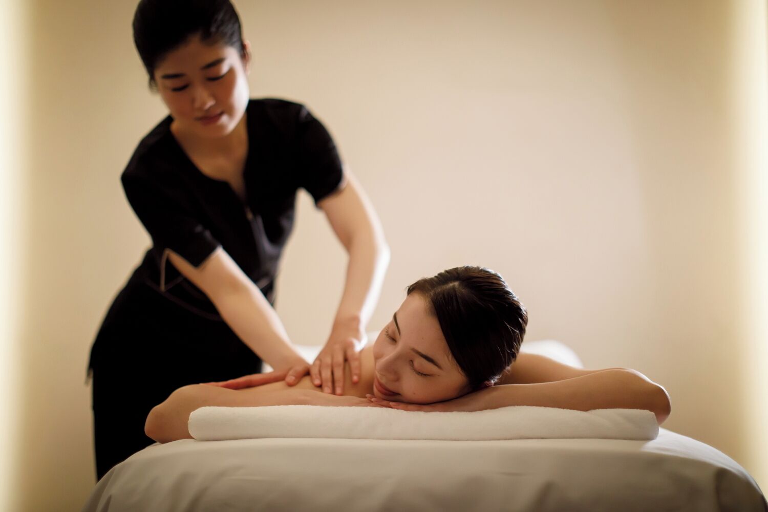 Une séance de massage dans une pièce comprenant un lit et un mur sobre.