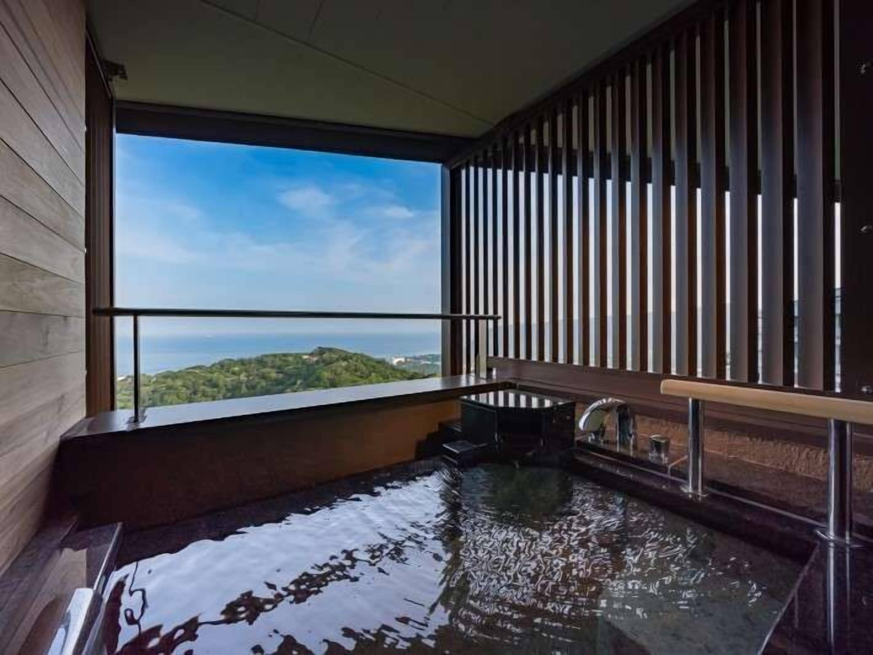 A modern bathroom with a large window, a wooden floor, and a bathtub.