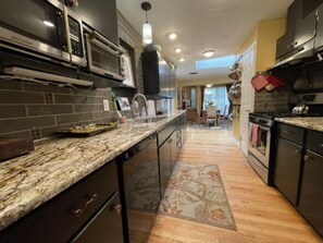 Una cocina moderna con armarios oscuros, una encimera de granito y una alfombra estampada.