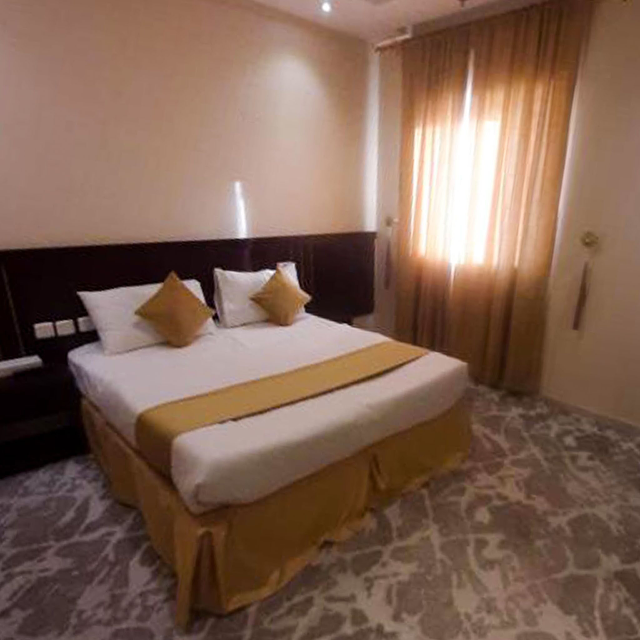 A hotel room with a large bed, a nightstand, and a window with curtains.