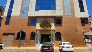 A tall building with a central glass facade, multiple floors, and a symmetrical design. - Taj Al Zahabiya Hotel (Makkah)