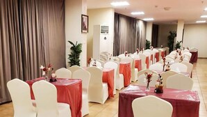 A banquet hall with rows of round tables covered with red tablecloths and white chairs. - Taj Al Zahabiya Hotel (Makkah)