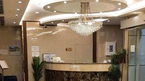 A hotel reception area with a curved reception desk, a chandelier, and a potted plant. - Taj Al Zahabiya Hotel (Makkah)