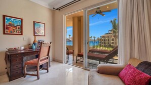 Une chambre équipée d’un bureau, d’une chaise et d’un canapé, avec vue sur un balcon et une piscine.