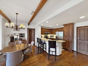 A spacious kitchen with wooden cabinets, a central island with bar stools, and a dining area with a round table and chairs.