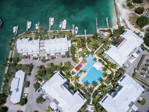 Une vue aérienne d’un complexe hôtelier comprenant plusieurs bâtiments, une piscine et des bateaux amarrés à un quai.