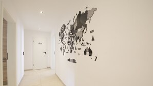 A hallway with a white door labeled "Bad" and a wall with a large abstract art piece. - 3-2-1meins Müngsten Bridge (Remscheid)