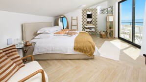 Un dormitorio moderno con una cama grande, una mesita de noche, una silla, un baño con ducha y un balcón con vistas.