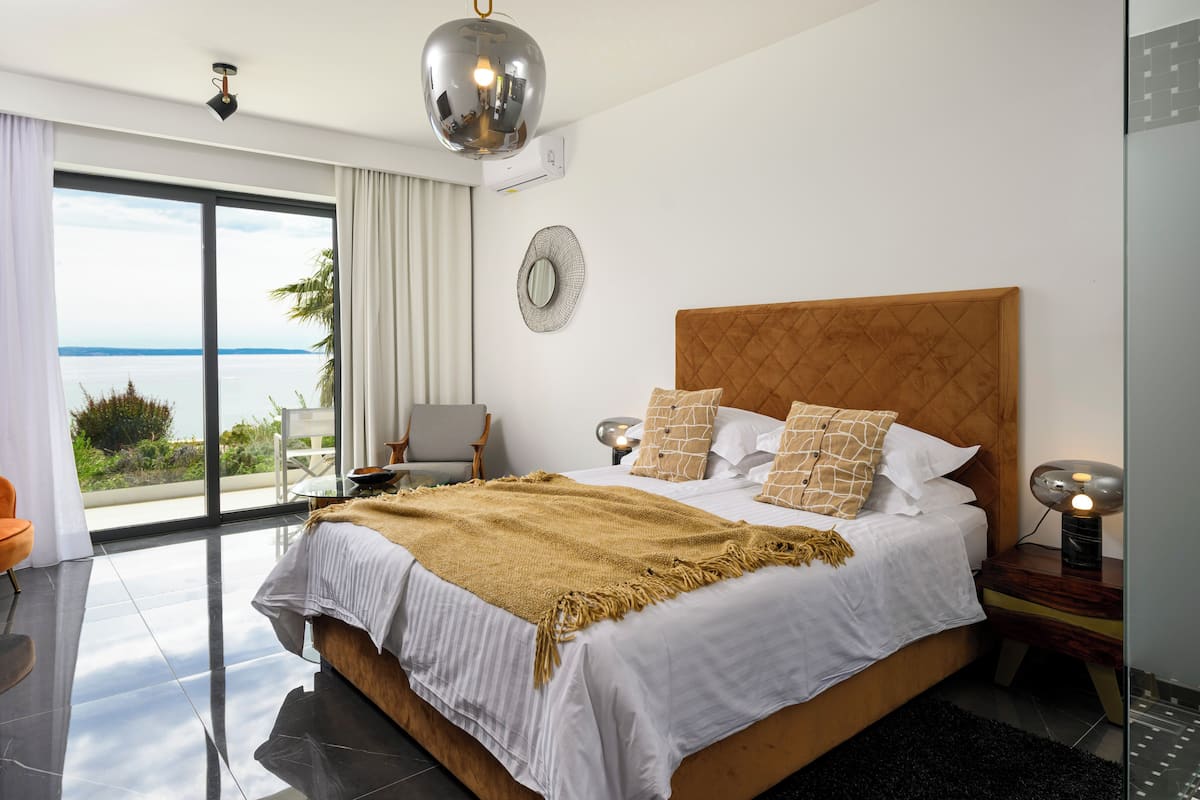Un dormitorio moderno con una cama grande, vistas al mar y un balcón.