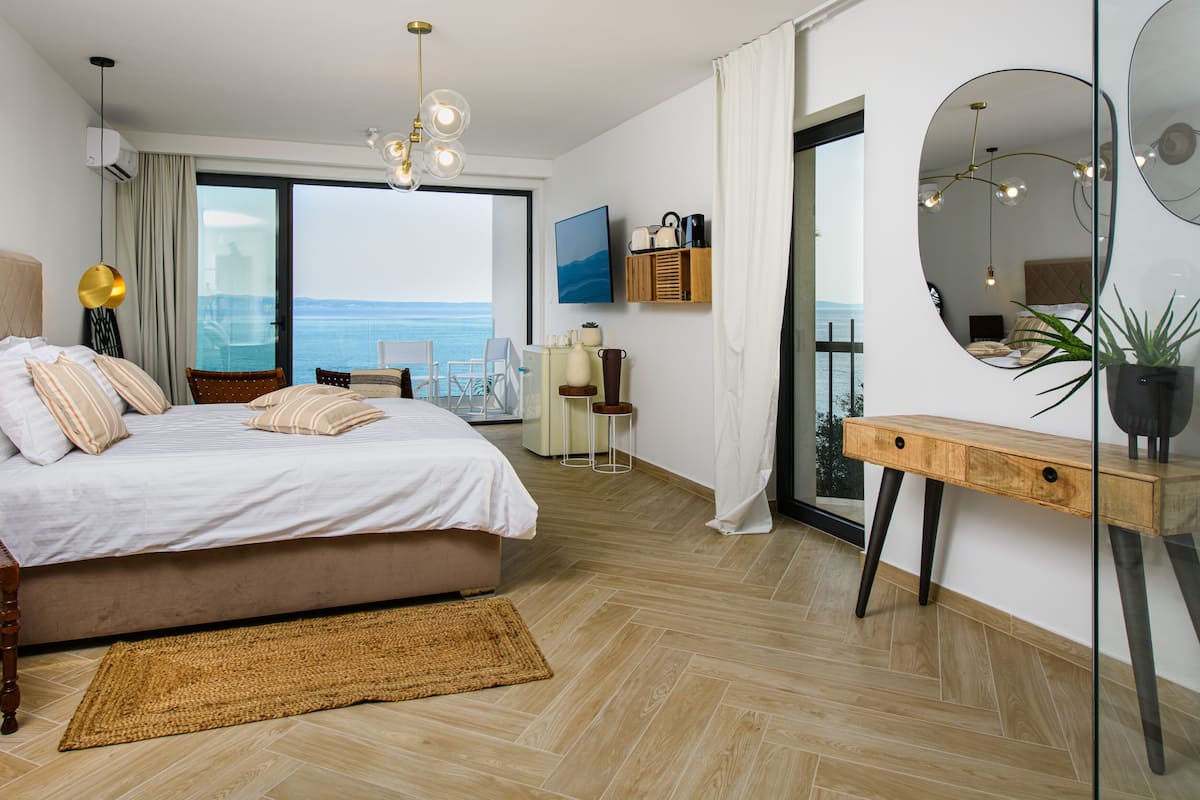 Un dormitorio moderno con una cama grande, vista al mar y un balcón.