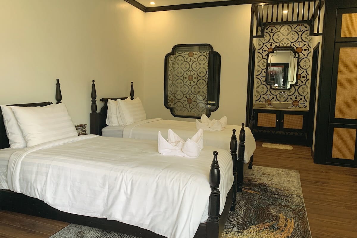 Habitación de hotel con dos camas, un espejo grande y un panel decorativo en la pared.