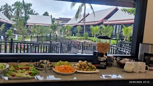 A dining area with a view of a traditional building and palm trees.