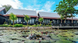 A building with a tiled roof, a stone wall, and a water feature with lily pads.
