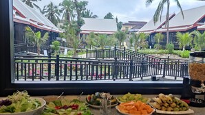 A buffet with various fruits and vegetables, a glass of water, and a bowl of salad.