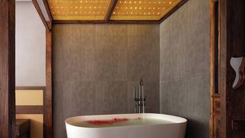 A modern bathroom with a freestanding bathtub, wooden beams, and a textured ceiling.