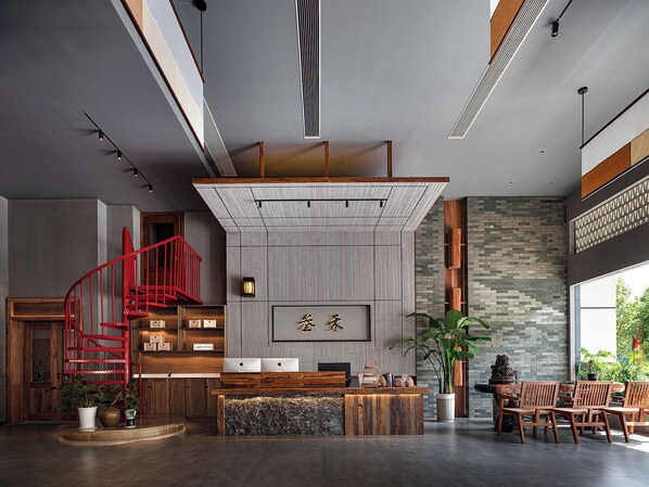 A modern reception area with a wooden reception desk, a red spiral staircase, and a large window providing a view of the outdoors.