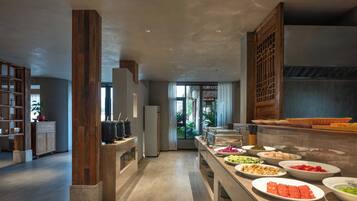 A modern hotel lobby with a buffet area featuring various food items and a large window providing a view of the outdoors.