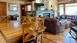 Amplia sala de estar con una mesa y sillas de madera, una chimenea de piedra y un cómodo conjunto de sofás.