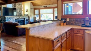 Una cocina amplia con armarios de madera, encimera de granito y chimenea de piedra.