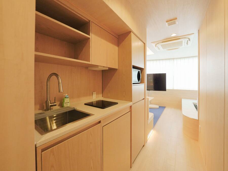 A compact kitchenette with a sink, microwave, and a flat-screen TV.