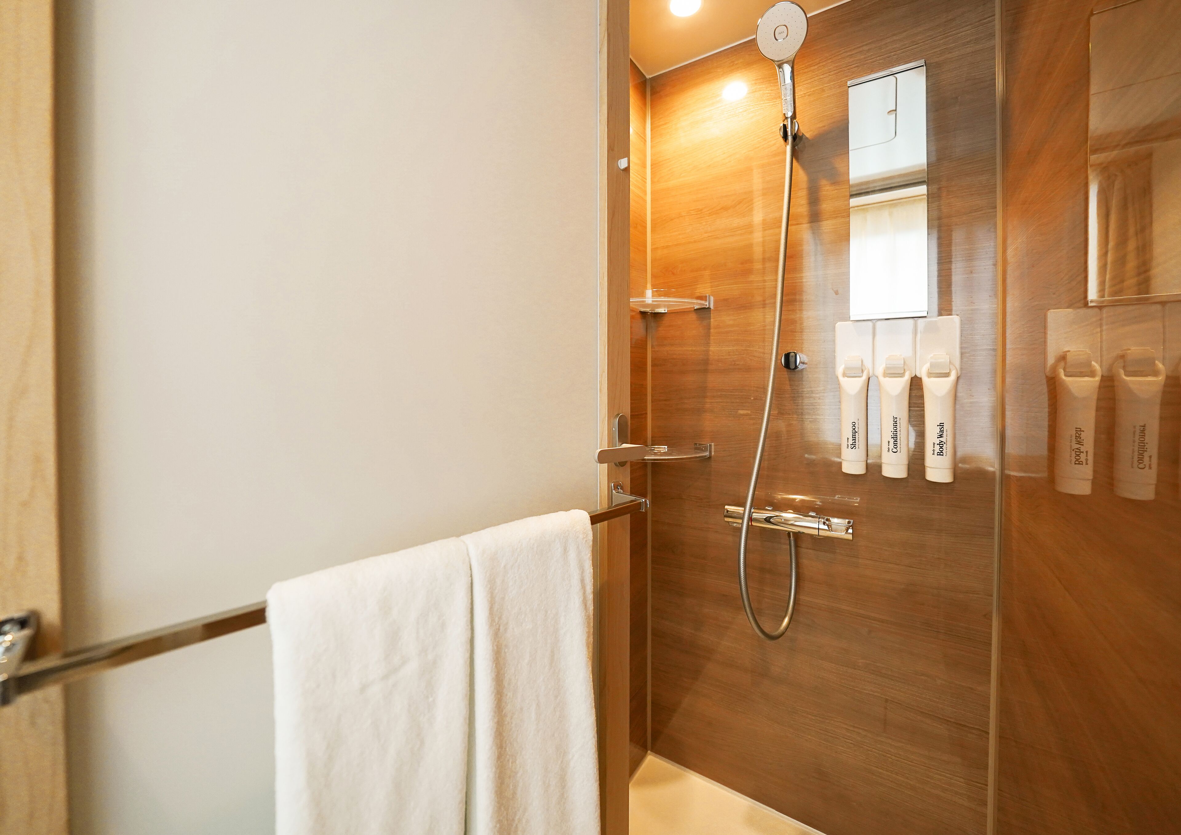 A bathroom with a wooden vanity, a towel rack, and a shower with a handheld showerhead.