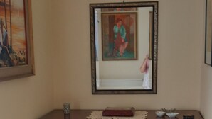 A wooden dresser with drawers and a decorative panel, a framed painting on the wall, and a bed with a patterned bedspread. -  Stay in the Heart of Agrigento, on Via Atenea, near the Valley of the Temples (Agrigento)
