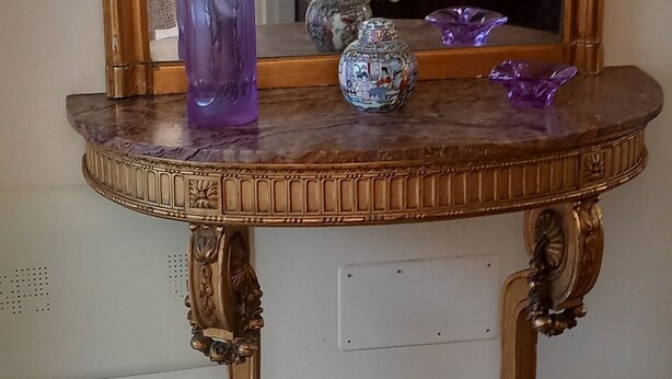 Une pièce avec une coiffeuse en bois, un grand miroir et un tableau encadré accroché au mur.