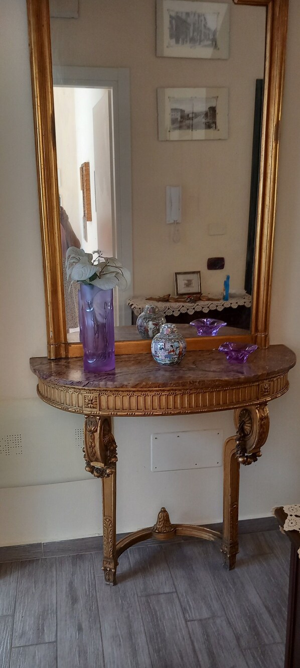 Una habitación con una mesa de tocador de madera, un espejo grande y un cuadro en la pared.