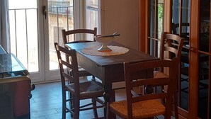 Un coin repas avec une table et des chaises, une lampe et une vue à travers une porte vitrée.