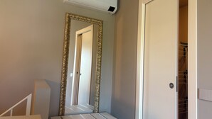 Une salle de bain avec un meuble-lavabo blanc, un miroir encadré d’or et un appareil de climatisation blanc placé au-dessus du miroir.