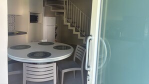 Une cuisine compacte comprenant un coin repas, un réfrigérateur et un escalier menant à l’étage supérieur.