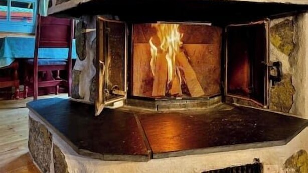Une cheminée en pierre dans laquelle brûle un feu.