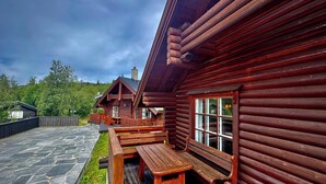 Une cabane en rondins dotée d’un espace extérieur aménagé et d’une terrasse pavée de pierres.