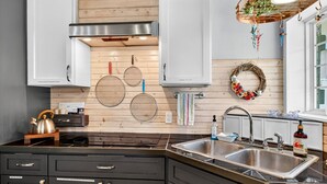 A modern kitchen with black cabinets, stainless steel appliances, and a wooden backsplash.