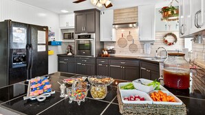 A modern kitchen with dark cabinets, stainless steel appliances, and a black refrigerator.
