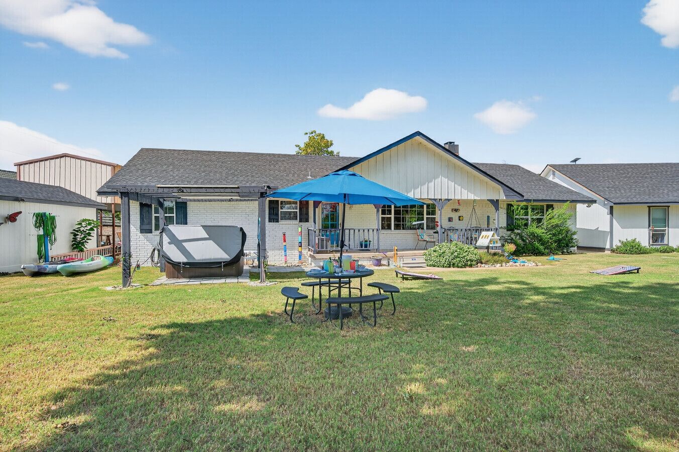 Een huis met een overdekt terras, een barbecue en een zwembad.