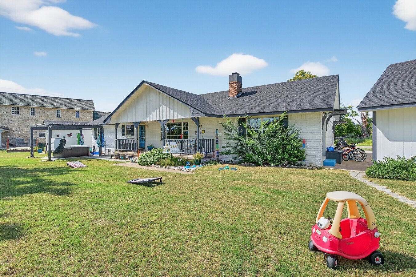 Une propriété résidentielle dotée d’un patio couvert, d’une maison de jeu et d’un petit jardin.