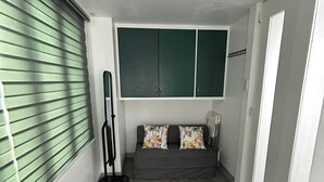 A room with a grey sofa, green cabinets, and a standing fan. - Simple but cozy, feel at home (Mandaluyong City)