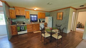 Una cocina con armarios de madera, estufa, microondas y una mesa de comedor con sillas.