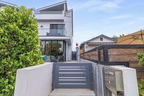 A modern two-story house with a gated entrance, a balcony, and a well-maintained garden.