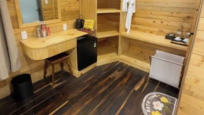 Baño de cabaña de madera con lavamanos, espejo y un refrigerador pequeño.