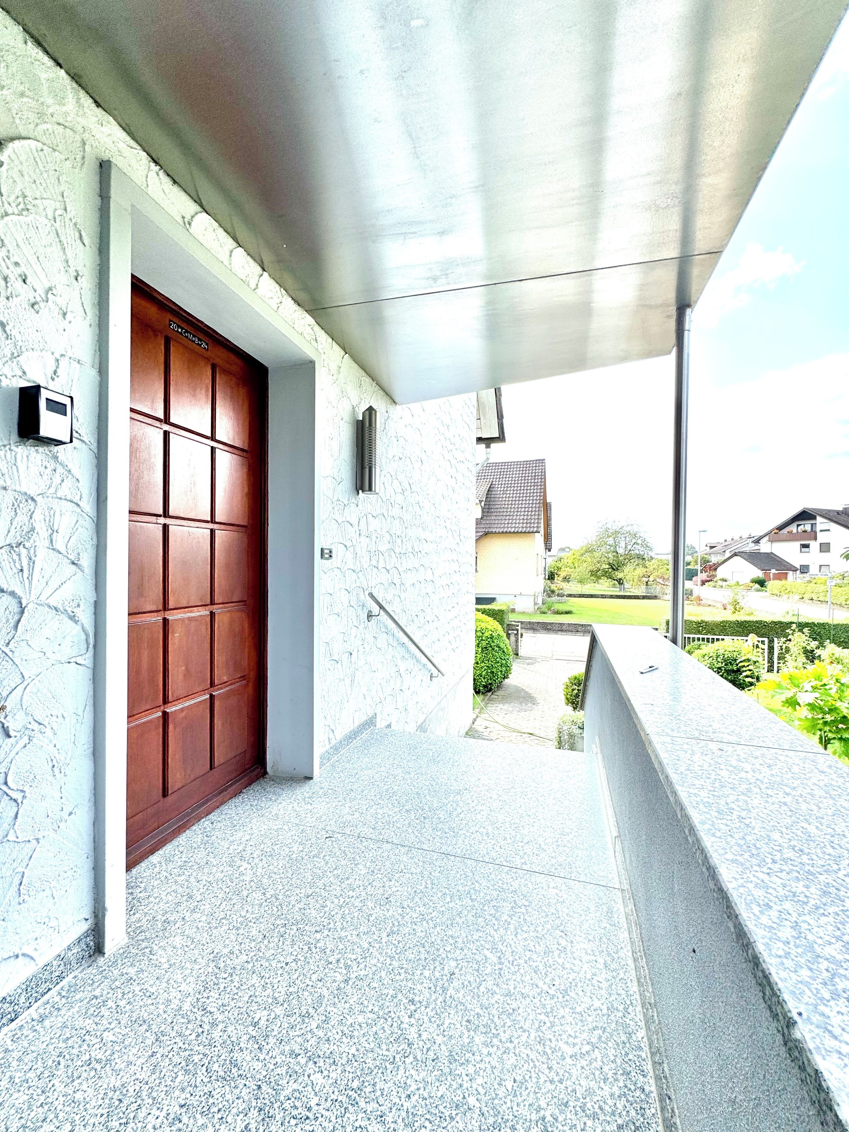 A covered outdoor area with a stone wall, a wooden door, and a concrete ledge.