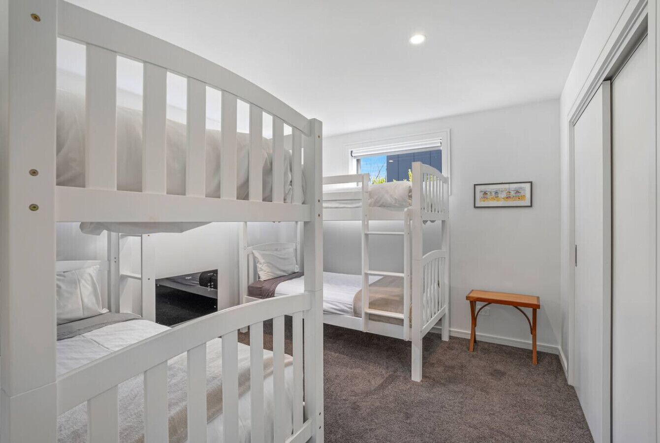 A room with bunk beds, a small wooden bench, and a window with a view.