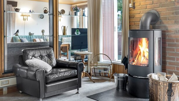 A cozy living room with a fireplace, leather sofa, and a glass display cabinet with decorative items.