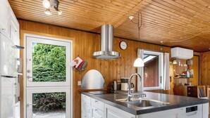 A modern kitchen with a central island, stainless steel appliances, and wooden paneling.