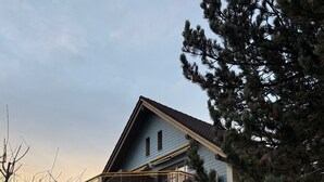 A two-story house with a balcony, a small patio with chairs, and a well-maintained lawn. - Directly at the Swiss Holiday Park - 3.5-room vacation apartment with 98 m² (Morschach)